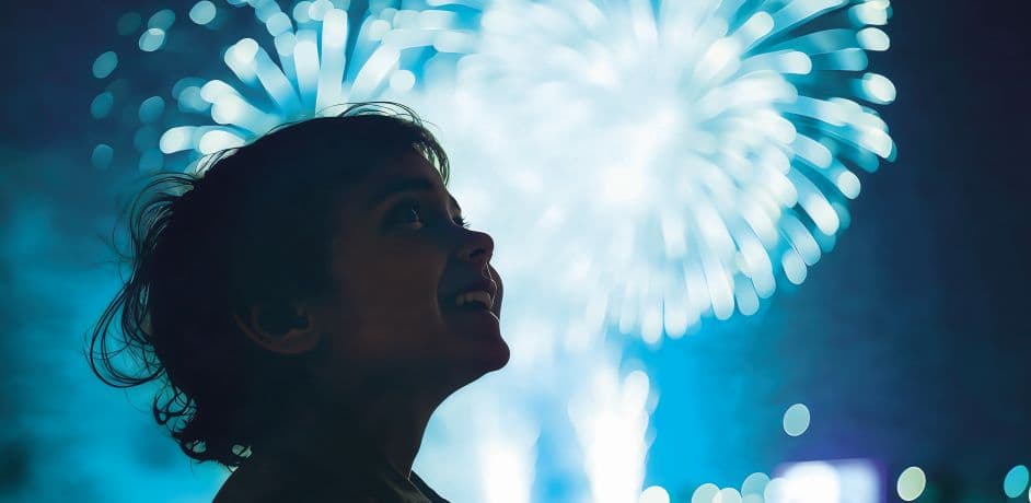 Ein Kind blickt in den Nachthimmel. Im Hintergrund ist ein Feuerwerk zu sehen. Ein Kind blickt in den Nachthimmel. Im Hintergrund ist ein Feuerwerk zu sehen.